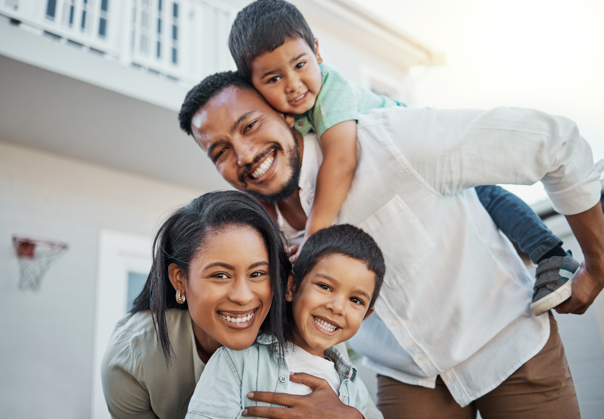 Portrait, happy family and piggyback outdoor at new home, real estate loan and building mortgage together. Parents, kids and smile outdoor for property investment, moving house and future security